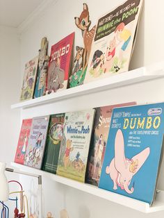 children's books are lined up on the wall above a shelf in a child's room