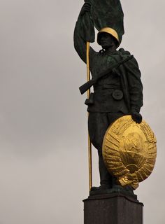 a statue with a flag on top of it's head and holding a pole