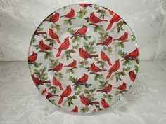 a plate with red birds and holly on it sitting on a white tablecloth background