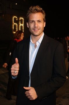 a man in a suit giving the thumbs up sign with his hand and wearing a ring