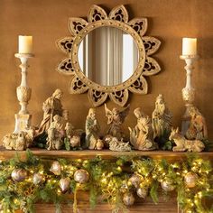 a mantle with candles and statues on it in front of a mirror that says christmas