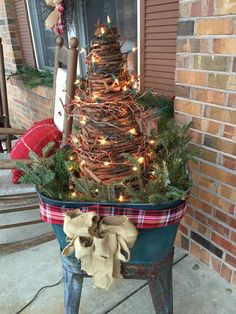 a potted christmas tree with lights in it on the side of a house outside