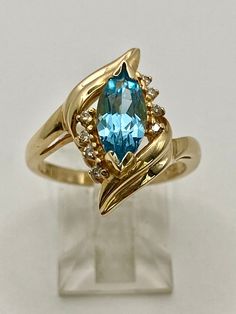 Add a touch of elegance to any special occasion with this beautiful ladies' 14K yellow gold ring. Featuring a stunning marquise shaped blue topaz stone, 8 diamonds, 4 on each side.  This ring is perfect for any occasion. The gemstone has a width of 5 mm and a length of 10 mm, complemented by a prong setting style. The ring is available in size 6.5, with a band width of 2 mm, and is sizable. Made of high-quality 14K gold and gemstone material, this full-finger or pinky ring is a beautiful addition to any jewelry collection. Fourth Anniversary, Traditional Anniversary Gifts, Topaz And Diamond Ring, Blue Topaz Stone, Topaz Stone, Beautiful Ladies, Pinky Ring, Yellow Gold Ring, Yellow Gold Rings