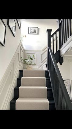 the stairs in this house are black and white with pictures on the wall above them