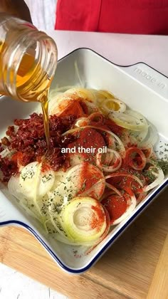 someone is pouring sauce on some food in a bowl with onions and other ingredients around it