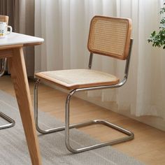 a wooden table with two chairs next to it and a potted plant in the corner