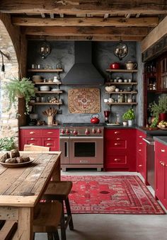 a kitchen with red cabinets, an oven and wooden table in front of the stove