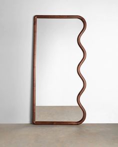 a wooden mirror sitting on top of a table next to a white wall and floor