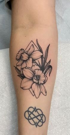 a black and white tattoo with flowers on the left leg, an intertwined heart in the middle