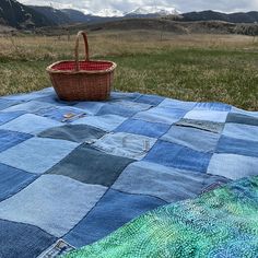 a basket sitting on top of a blue blanket in the middle of a grassy field