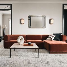 a living room with a couch, coffee table and mirror on the wall above it