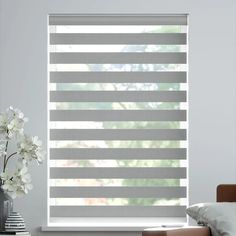 a living room with white flowers and gray blinds