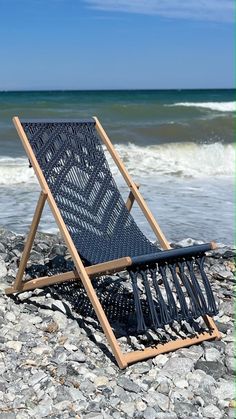 a chair sitting on top of a rocky beach next to the ocean