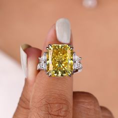 a woman's hand holding a fancy yellow diamond ring