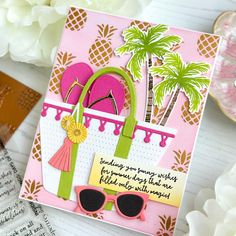 a handmade card with sunglasses, palm trees and a pink purse on the table