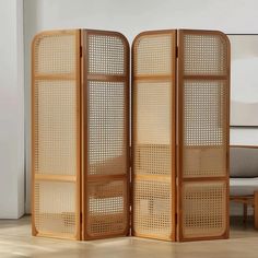 a room divider made out of wood and wickers in front of a couch