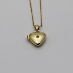 A tiny gold vermeil (gold plated sterling silver) heart locket opens to hold two photos or keepsakes.  It features cubic zirconia stone. Measurements: Chain: 16" Locket: 1/2" Gold Heart Cut Locket Necklace For Keepsake, Gold Heart-cut Locket Necklace For Gift, Heart-shaped Yellow Gold Keepsake Charm Necklace, Gold Pendant Locket Necklace With Birthstone, Yellow Gold Heart Locket Necklace For Keepsake, Gold Locket Necklace With Birthstone For Keepsake, Gold Heart Necklace With Birthstone For Keepsake, Gold Heart Locket Necklace With Heart Charm, Gold Heart Charm Necklaces With Birthstone