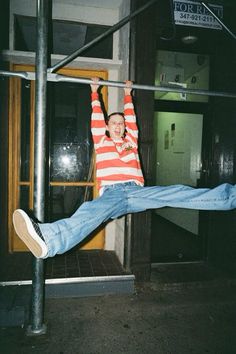 a man is hanging upside down on a metal pole with his arms in the air