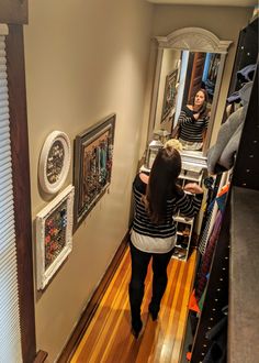 a woman is walking down the hallway in front of a mirror