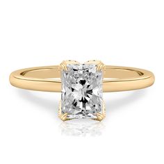 a yellow gold engagement ring with a princess cut diamond in the center, on a white background