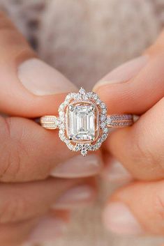 a close up of a person holding a ring with an emerald stone in the center