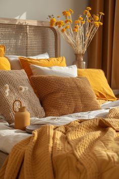 a bed with yellow pillows and blankets on it