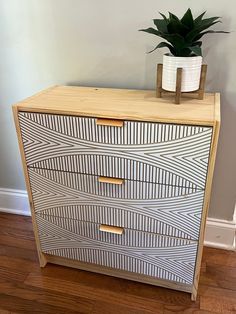 a wooden dresser with two drawers and a potted plant sitting on top of it