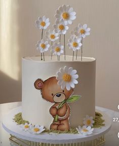 there is a cake decorated with flowers and a teddy bear on the top one side