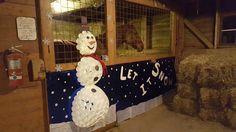 a snowman made out of plastic sitting next to hay bales in a barn