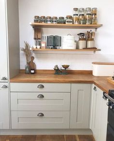 a kitchen with white cabinets and open shelves on the wall, along with wooden flooring