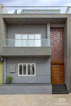 a grey house with a wooden door and window on the second floor that is made out of concrete