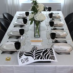 the table is set with black and white place settings, silverware, and flowers