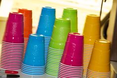 there are many different colored cups on the table