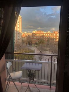 a balcony with an ironing board and chair on it, looking out onto the city