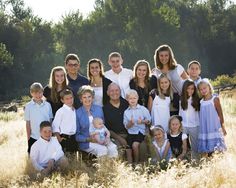 a large group of people posing for a photo in the middle of some tall grass