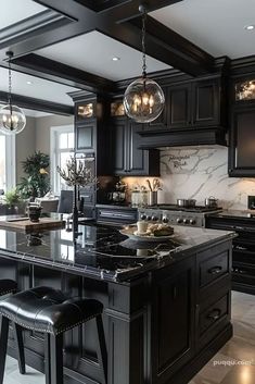 a large kitchen with black cabinets and marble counter tops, an island in the middle