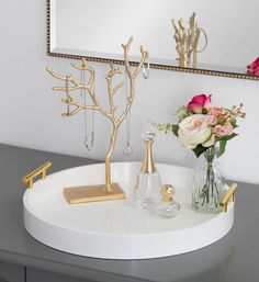 there is a vase with flowers and jewelry on the table in front of the mirror