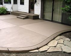 a concrete patio with steps leading up to the front door and back porch area,