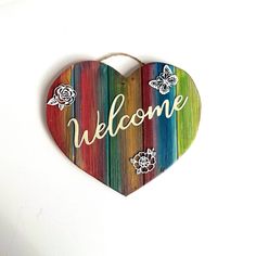 a wooden heart with the word welcome painted on it