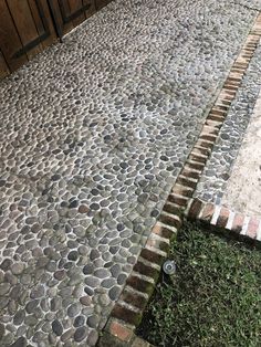 an empty bench sitting on the side of a cobblestone road next to a wooden fence