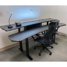 an office desk with a computer on it and a black chair in front of it