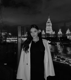 a woman standing on top of a roof next to a cityscape at night