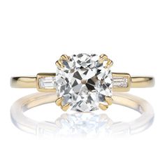 a yellow gold engagement ring with an oval cut diamond and baguets on the side