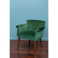 a green chair sitting on top of a hard wood floor next to a blue wall