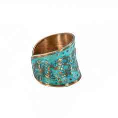 a gold and turquoise ring with an intricate design on the inside, sitting against a white background