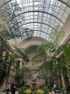 the inside of a building with plants and people walking around