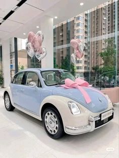 a blue car with pink bows and balloons