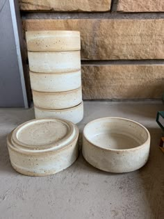 a stack of white bowls sitting on top of a floor next to a book shelf