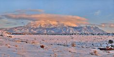 a snow covered field with mountains in the background