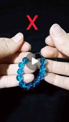 two hands holding blue beads with red x on them